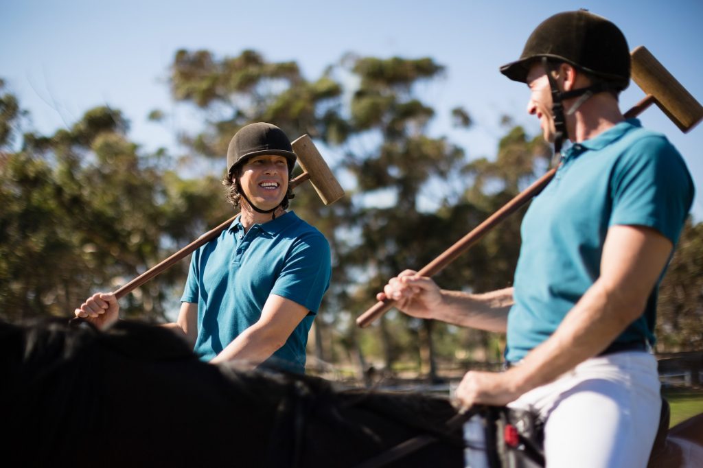 Two male jockeys riding horse in the ranch